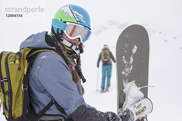 Nahaufnahme eines Mädchens in Skikleidung mit Snowboard