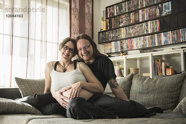 Porträt eines schwangeren Paares  das sich auf der Couch entspannt