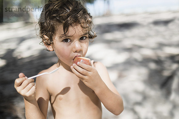 Porträt eines kleinen Jungen  der eine Passionsfrucht isst