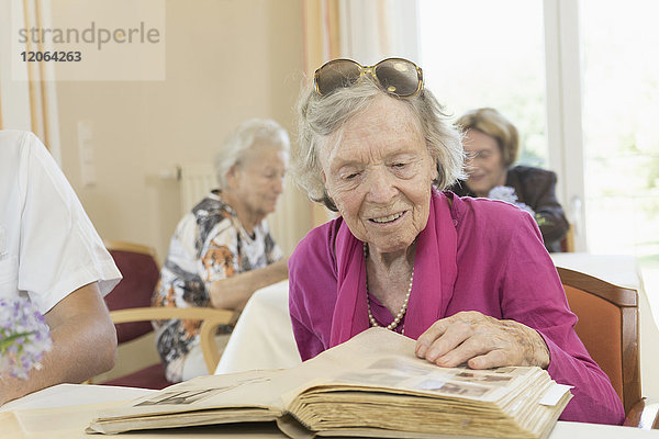 Ältere Frau betrachtet Fotoalbum im Altersheim