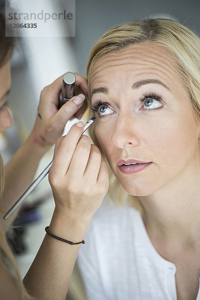 Frau lässt sich von einem Stylisten schminken