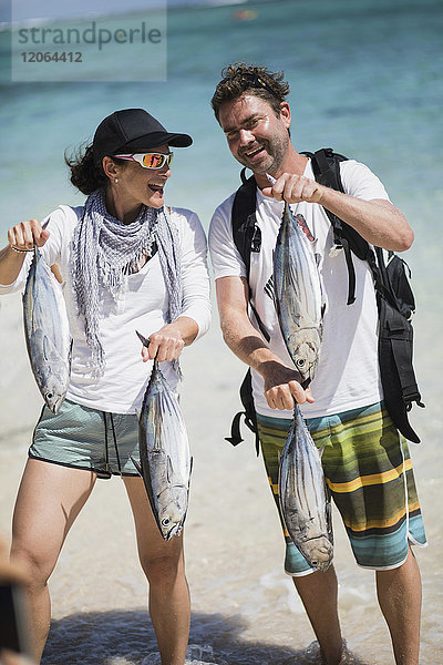 Mann und Frau mit frischem Fisch am Strand