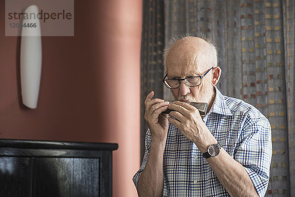 Älterer Mann bläst ein Mundharmonika-Instrument