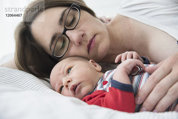 Mutter schläft mit ihrem neugeborenen Jungen im Bett