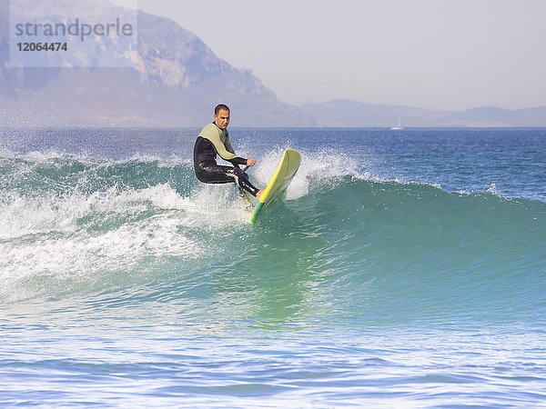 Mann Surfer sehnt sich nach der Spitze der Welle am Strand von Sopelana