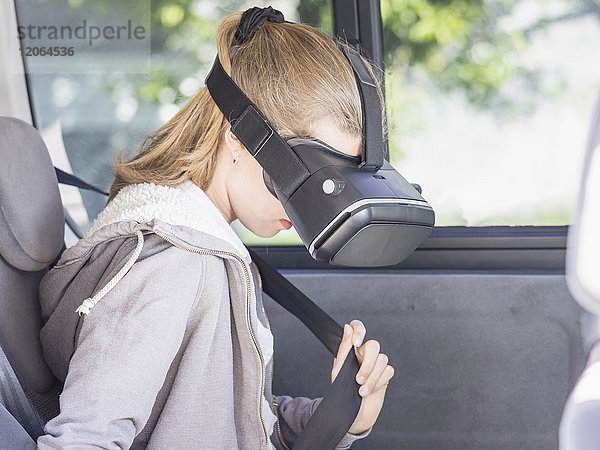 Mädchen mit Virtual-Reality-Headset beim Einstellen des Sicherheitsgurts im Auto