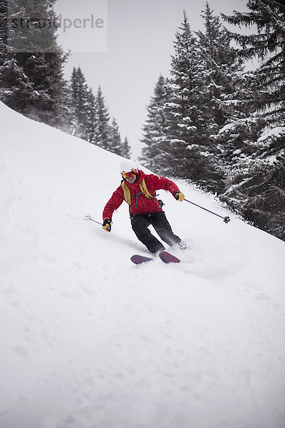 Mann beim Skifahren bergab auf Schnee