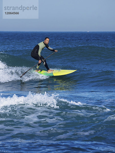 Mann beim Surfen mit einem Stand Up Paddling Board am Strand von Sopelana