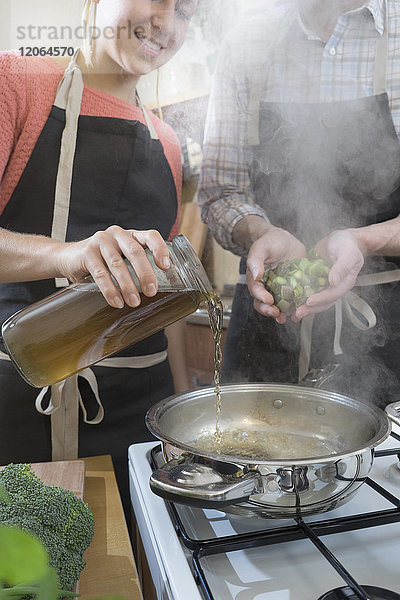 Paar füllt heiße Pfanne mit Brühe und Spargel