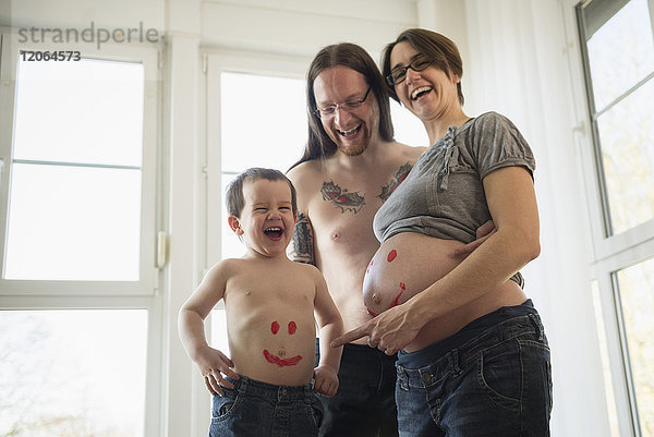Mann mit schwangerer Frau und Sohnes Bauch mit Smiley bemalt