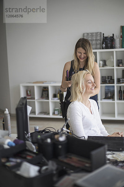 Friseurin glättet das Haar einer Frau im Friseursalon