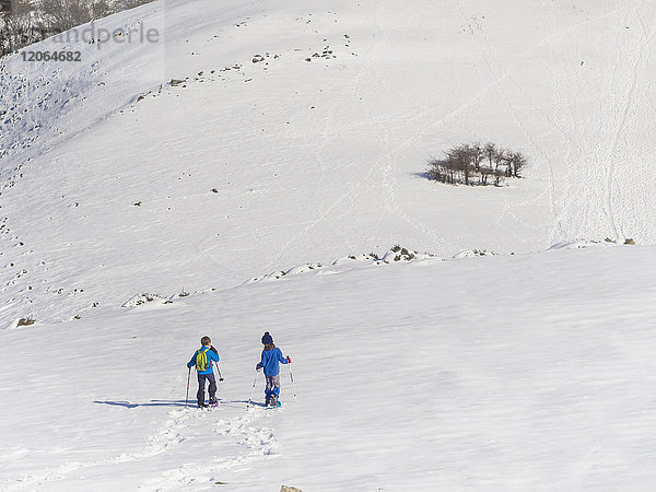 Junge und Mädchen mit Schneeschuhen beim Spaziergang über das Schneefeld am Berg Anboto