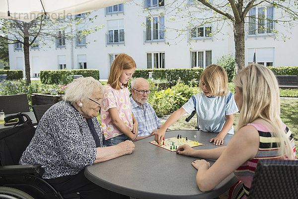 Mehrgenerationenfamilie spielt Brettspiel im Pflegeheim