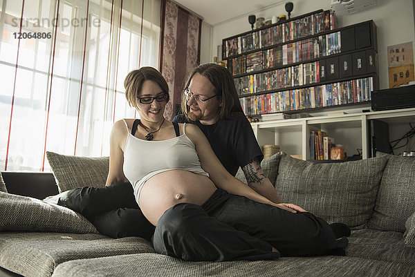 Ein schwangeres Paar entspannt sich auf der Couch