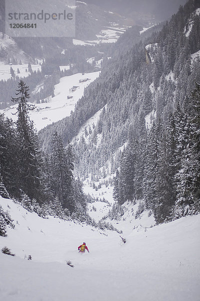 Mann beim Skifahren bergab auf Schnee