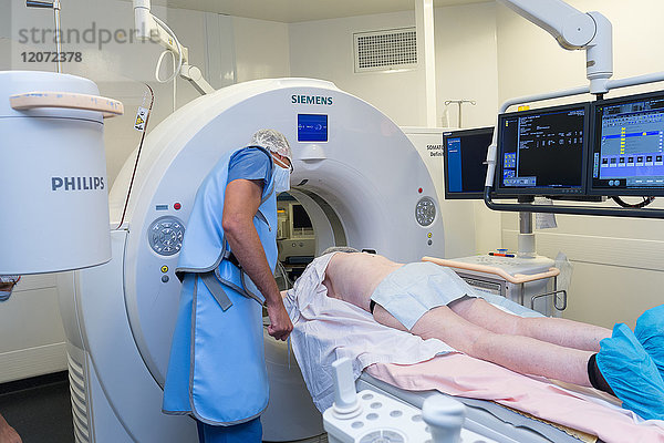 Reportage aus der Abteilung für interventionelle Scanner im Krankenhaus Pasteur 2  Nizza  Frankreich. Vertebroplastie - Zementplastik-Operation zur Behandlung einer Wirbelfraktur. Die Technik besteht darin  unter Bildführung eine biokompatible Zementmischung in den geschwächten Wirbel zu injizieren  um ihn zu konsolidieren. Der Radiologe trägt eine Röntgenschutzschürze  um sich vor den Strahlen zu schützen.