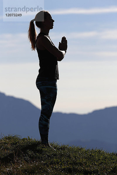Eine Frau nimmt auf einem Berggipfel eine Hatha-Yoga-Pose ein. Französische Alpen. Frankreich.