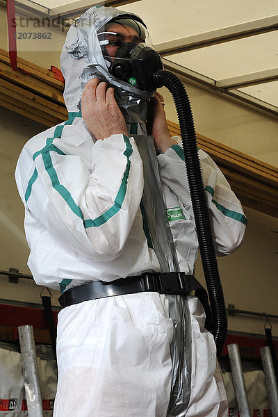 Vorbereitung eines Arbeiters auf einer Asbestsanierungsbaustelle in Nordfrankreich. Die vorgeschriebene Kleidung für jeden Arbeiter besteht aus einem Overall  einer Maske  Stiefeln und Handschuhen.