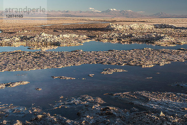 Aufgeschüttete Salzreste an der Laguna Chaxa  Atacama Salt Flats  mit schneebedeckten Vulkanen  in der Nähe von San Pedro de Atacama  Chile  Südamerika