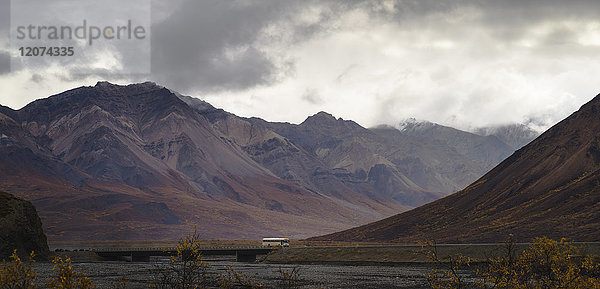 Touristenbus  der zwischen Bergen im Denali-Nationalpark fährt  Alaska  Vereinigte Staaten von Amerika  Nordamerika