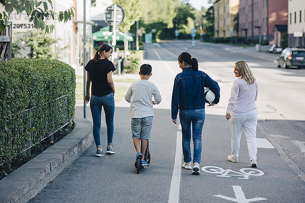 Rückansicht der Familienwanderung auf dem Fahrradweg in der Stadt bei Sonnenschein