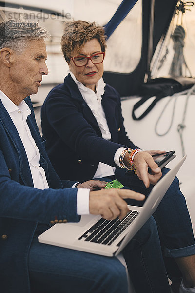 Senior Paar diskutiert über Laptop während der Reise in der Yacht