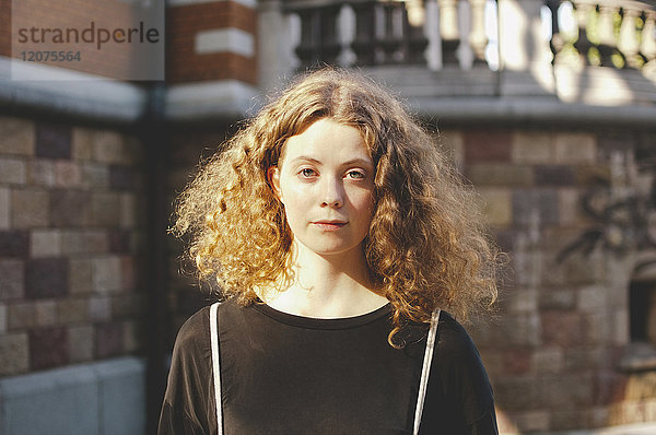 Portrait einer jungen Studentin mit braunen Haaren außerhalb der Universität
