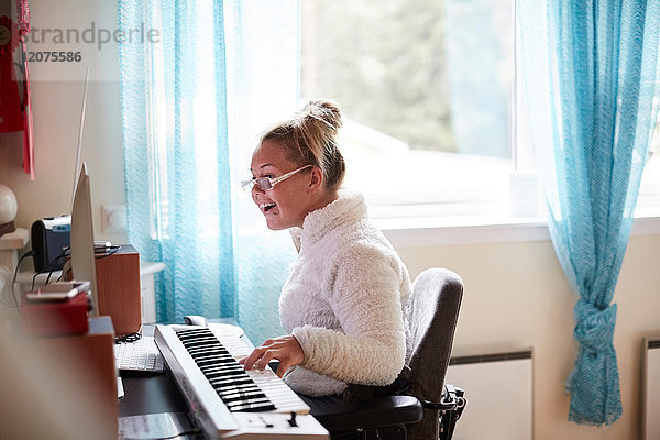 Behinderte junge Frau beim Klavierspielen zu Hause