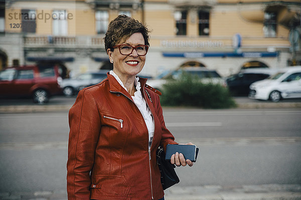 Porträt einer lächelnden Seniorin in brauner Jacke an der Stadtstraße