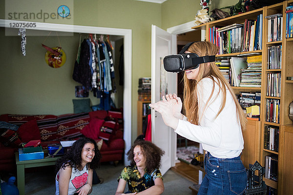 Blondes Mädchen mit Virtual-Reality-Headset  während Freunde zu Hause sitzen