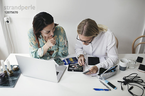 High-Winkel-Ansicht von weiblichen Ingenieuren bei der Arbeit an der Festplatte am Tisch im Home-Office
