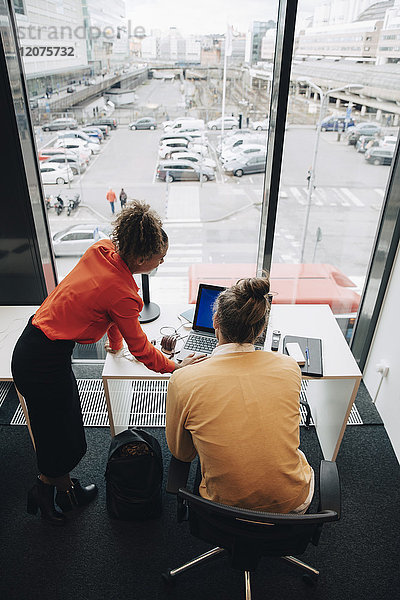 Hochwinkelansicht von multiethnischen Kollegen mit Laptop am Schreibtisch im Büro