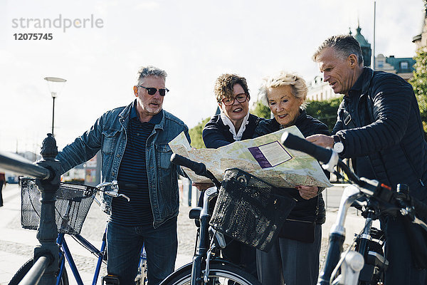 Seniorenfreundinnen und Senioren mit Fahrrädern beim Kartenlesen in der Stadt