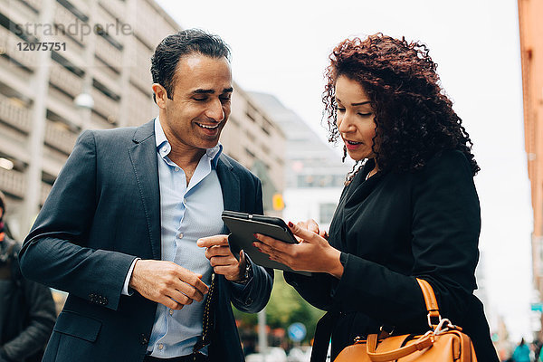Low-Winkel-Ansicht der Geschäftsfrau diskutieren über digitale Tablette zu Geschäftsmann  während auf dem Bürgersteig in der Stadt stehen