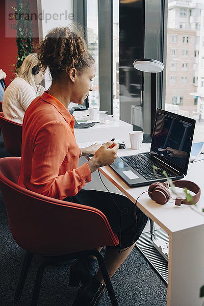 Seitenansicht der Geschäftsfrau mit Laptop am Schreibtisch im Büro