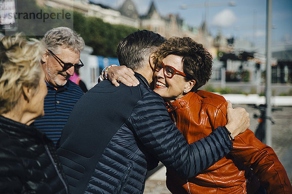 Glückliche Seniorin umarmt den Mann von Freunden in der Stadt während des Urlaubs.