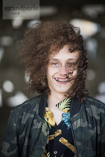 Porträt eines lächelnden Teenagers mit lockigen braunen Haaren im Parkhaus
