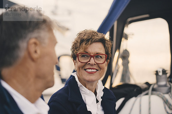 Lächelnde ältere Frau  die den Mann beim Reisen auf der Yacht ansieht.