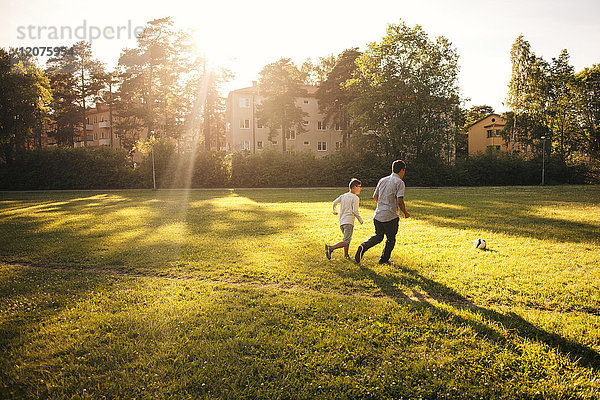 Väter und Söhne spielen an sonnigen Tagen Fußball auf der Wiese.