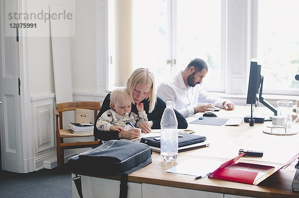 Mittlere erwachsene Geschäftsfrau mit kleinem Mädchen am Tisch im Kreativbüro