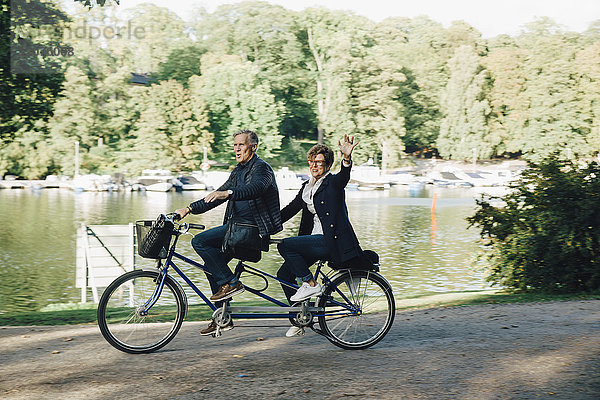 Seniorenpaar genießt Tandem-Radtour am Teich im Park