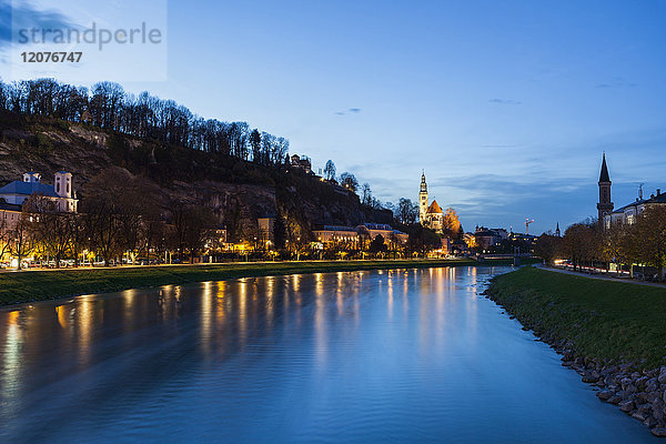 Österreich  Salzburg  Fluss und beleuchtetes Flussufer in der Abenddämmerung