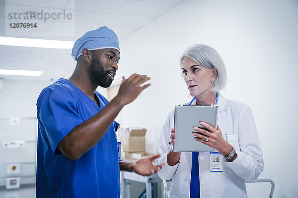 Arzt und Krankenschwester diskutieren über das digitale Tablet