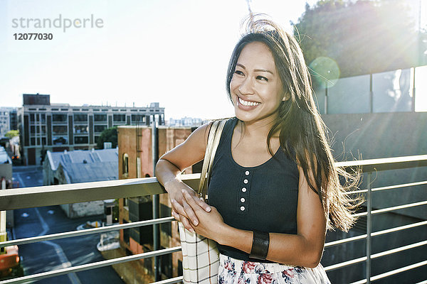 Lächelnde asiatische Frau lehnt sich auf dem Dach