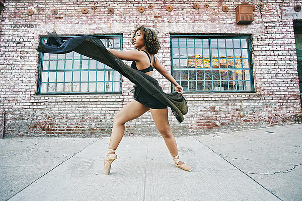 Gemischtrassige Frau tanzt Ballett auf dem Bürgersteig