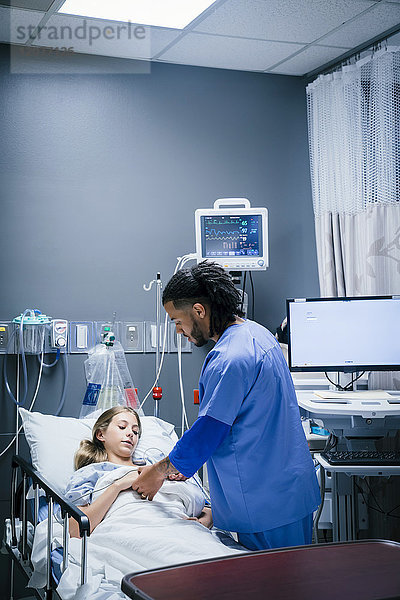 Krankenschwester hält Hand eines Patienten im Krankenhaus