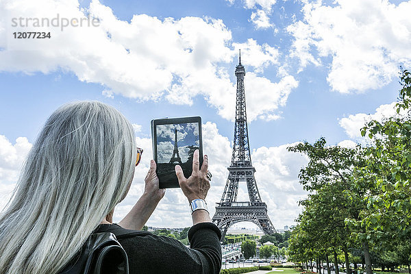 Kaukasische Frau fotografiert den Eiffelturm mit einem digitalen Tablet