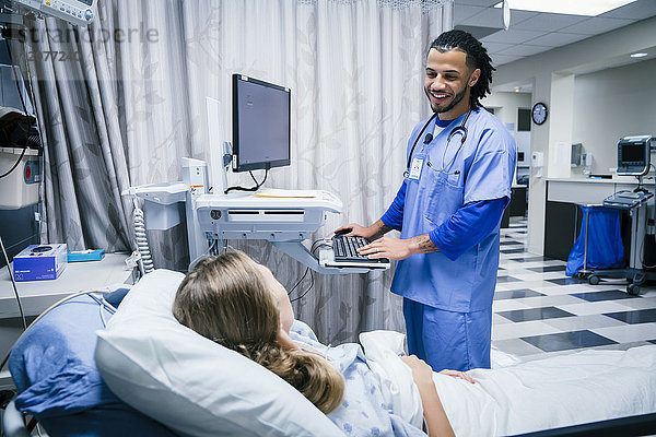 Krankenschwester spricht mit Patient im Krankenhausbett