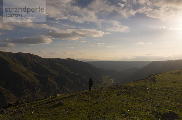 Entfernter kaukasischer Mann  der die malerische Aussicht auf ein Tal bewundert