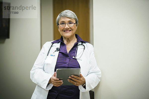 Porträt eines lächelnden gemischtrassigen Arztes mit digitalem Tablet